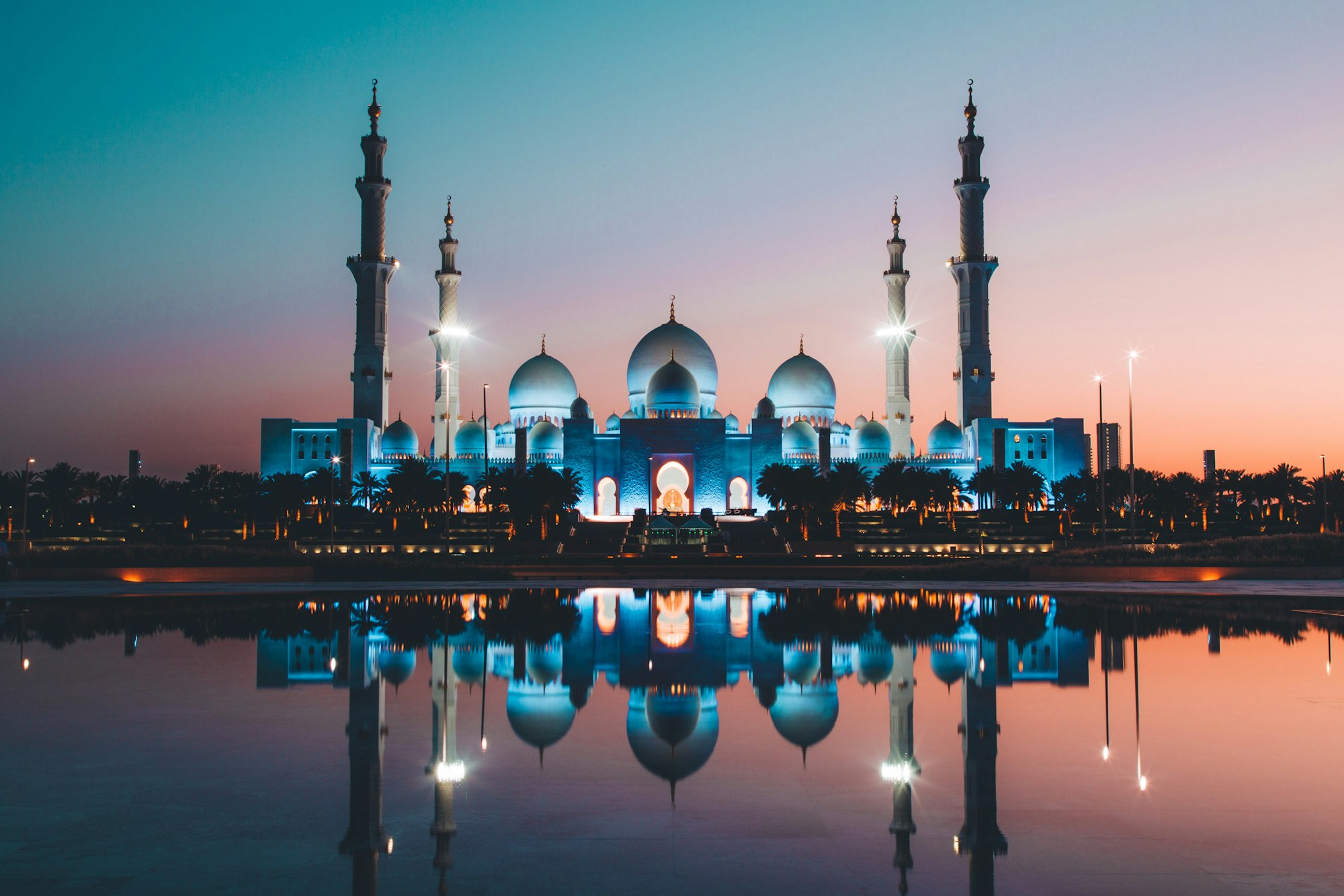 Grand mosque and minarets reflected in still water at dusk